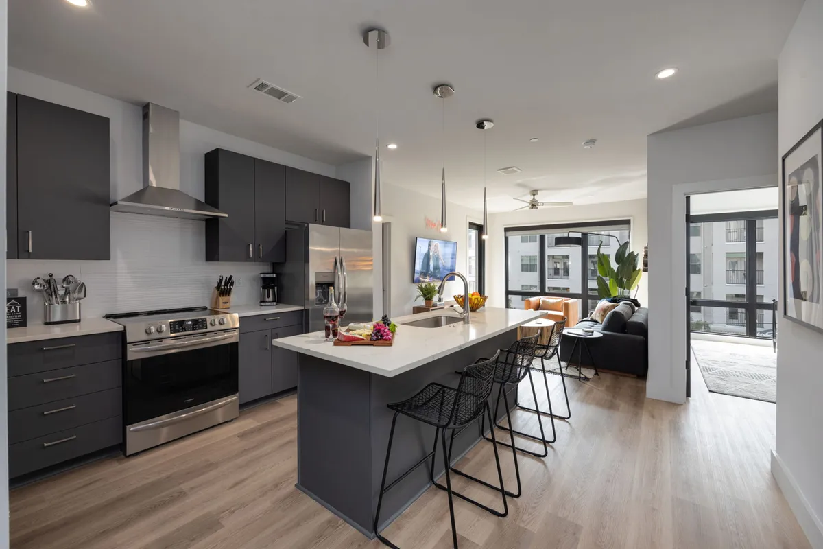 Contemporary kitchen with a central island, bar stools, and large windows adjacent to the living area. The space is bright and inviting, ideal for entertaining, preparing meals, or enjoying morning coffee while soaking in the urban view.