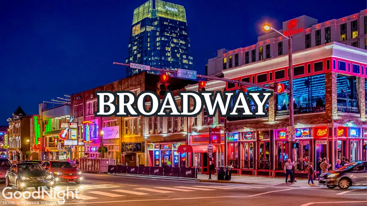 Lively street view with neon signs, bustling building facades, people walking, and traffic signals—evoking the excitement of Nashville’s nightlife and renowned entertainment scene.